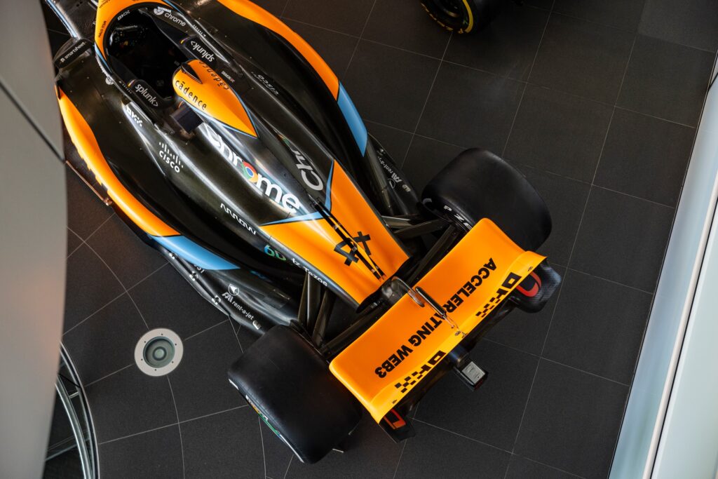 Close overhead view of the orange and black 2023 McLaren MCL37A Formula 1 car, showing its engine cover and rear wing