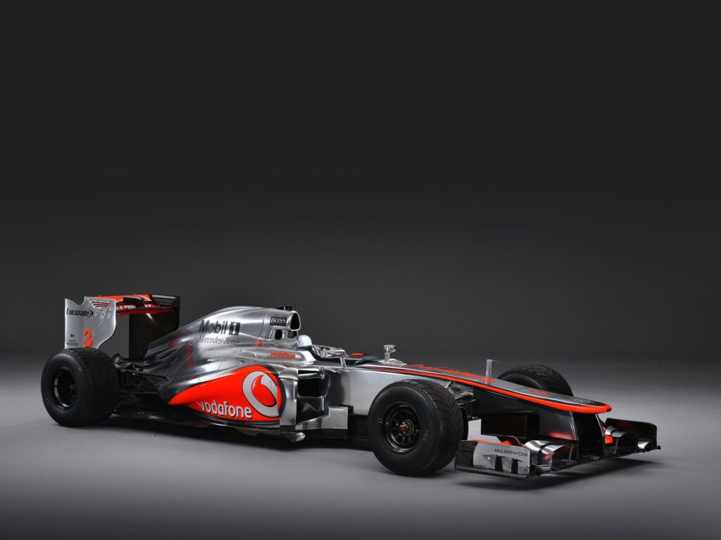 Studio front three-quarter view of a silver and red 2012 McLaren MP4/27 Formula 1 car against a grey background