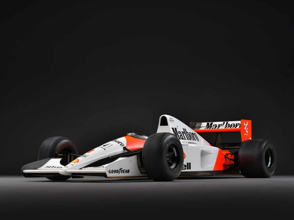 Studio side view of a red-and-white 1991 McLaren MP4/6 Formula 1 car against a dark background